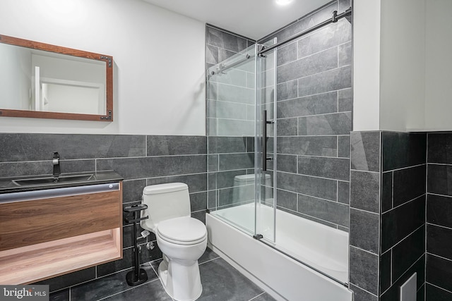 1143 Tasker St, Philadelphia, PA 19148 - full bathroom with a wainscoted wall, bath / shower combo with glass door, toilet, tile walls, and vanity