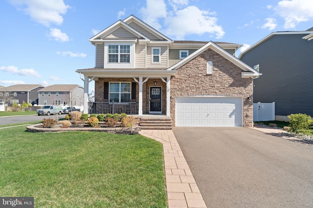 craftsman house featuring a front yard, stone siding, covered porch, and driveway