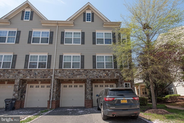 view of property with stone siding, driveway, and a garage