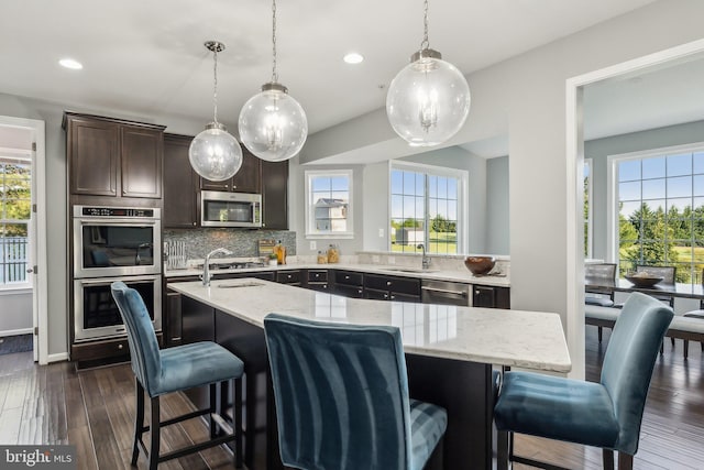 kitchen with a sink, appliances with stainless steel finishes, recessed lighting, and light stone counters