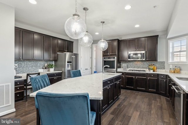 kitchen featuring visible vents, appliances with stainless steel finishes, light stone counters, and tasteful backsplash