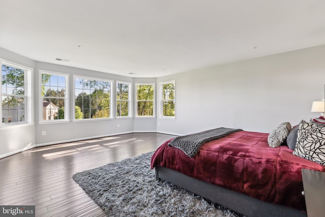 bedroom featuring baseboards, visible vents, multiple windows, and wood finished floors