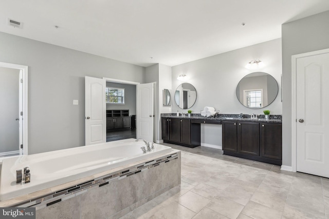 full bath with double vanity, a bath, visible vents, tile patterned flooring, and a sink