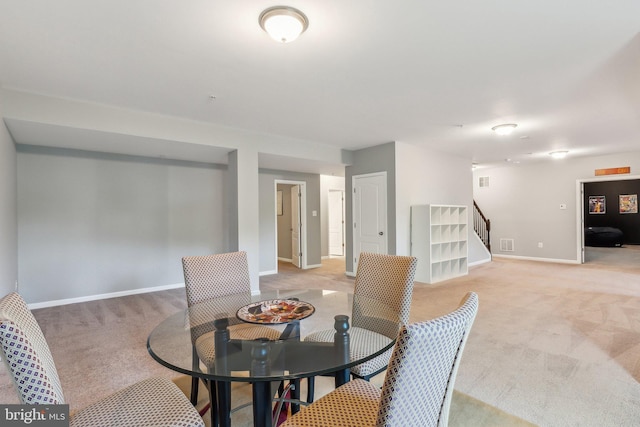 dining room featuring baseboards, stairs, visible vents, and light carpet