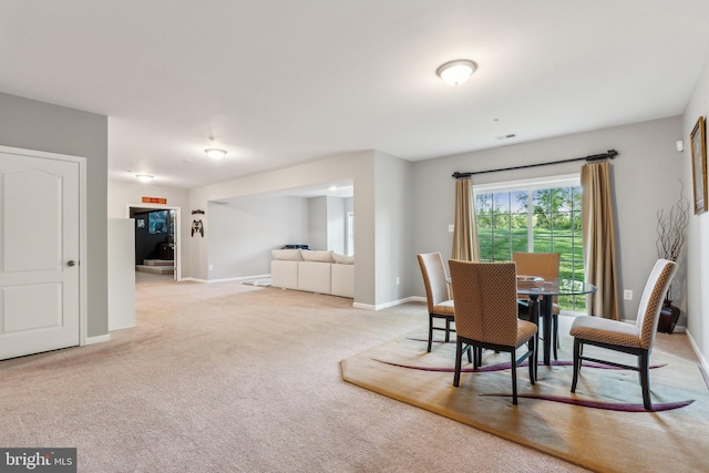 dining area with baseboards and light colored carpet