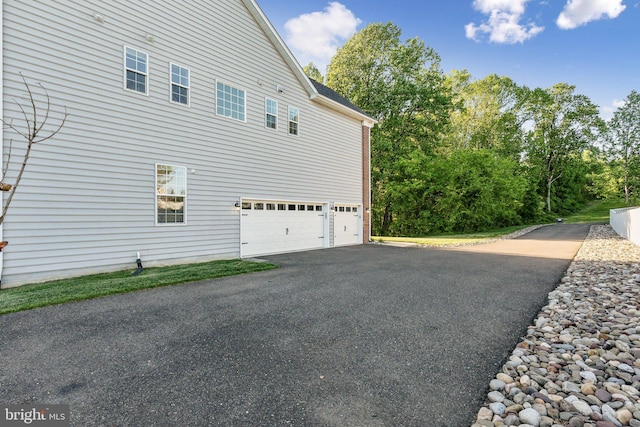view of side of home featuring a garage and aphalt driveway