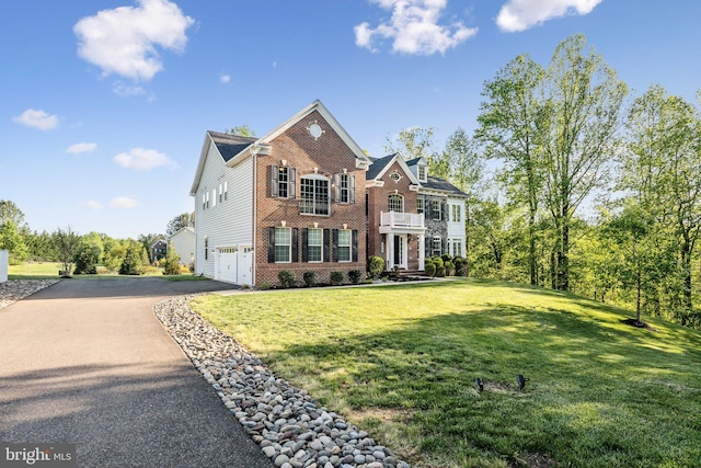 view of front of property featuring brick siding, a garage, a front yard, a balcony, and driveway