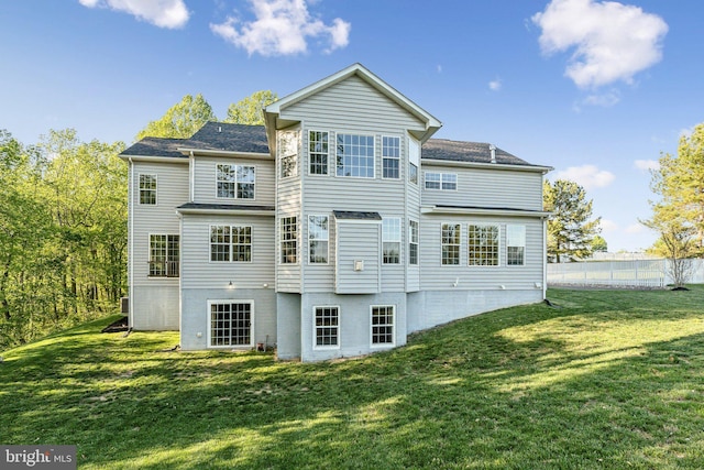 back of property with a lawn and fence