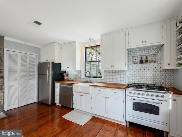 kitchen featuring appliances with stainless steel finishes, butcher block counters, visible vents, and a sink