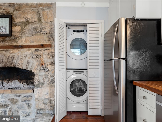 washroom with dark wood-style flooring, stacked washer and dryer, and laundry area