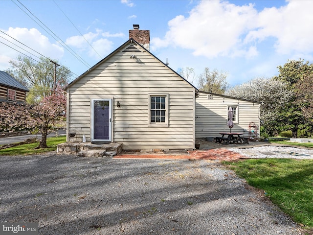 back of property with a chimney and a patio