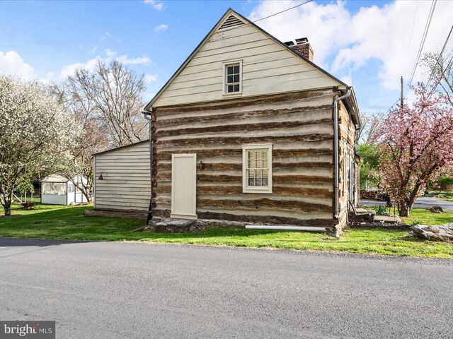 view of side of home with a yard and a chimney