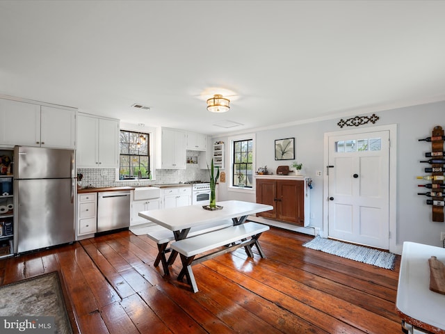 kitchen featuring white cabinets, stainless steel appliances, dark wood finished floors, tasteful backsplash, and visible vents
