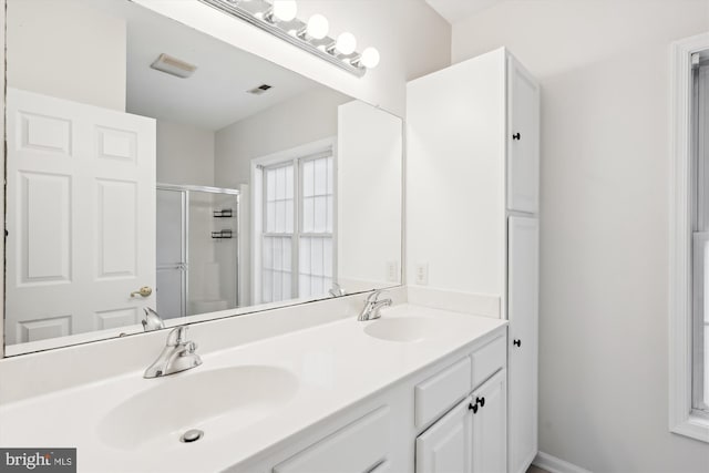 bathroom featuring visible vents, a sink, a shower stall, and double vanity