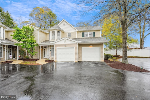 multi unit property with an attached garage, driveway, fence, and roof with shingles