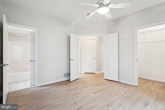 unfurnished bedroom featuring baseboards, visible vents, light wood-style floors, and a walk in closet