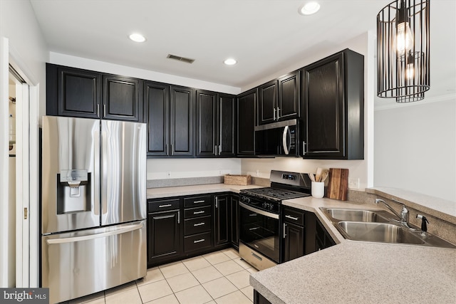 kitchen featuring a sink, light tile patterned floors, stainless steel appliances, dark cabinetry, and light countertops