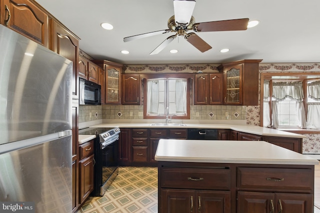 kitchen with a wealth of natural light, light countertops, and black appliances