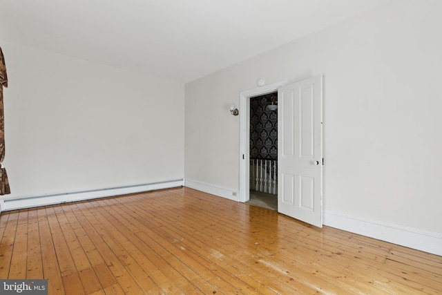 spare room featuring light wood-style flooring, a baseboard radiator, and baseboards