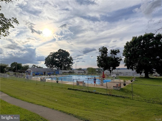 view of community with a yard, a swimming pool, and fence