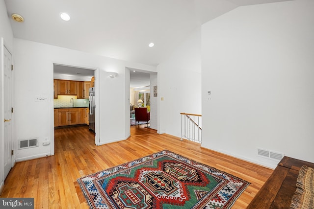 sitting room featuring visible vents, an upstairs landing, and lofted ceiling