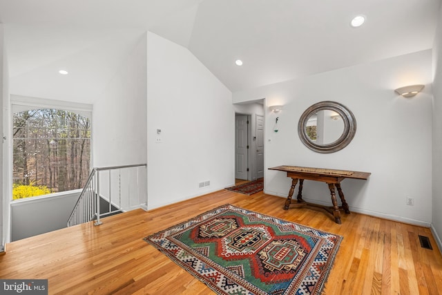 hall featuring visible vents, an upstairs landing, wood finished floors, and vaulted ceiling