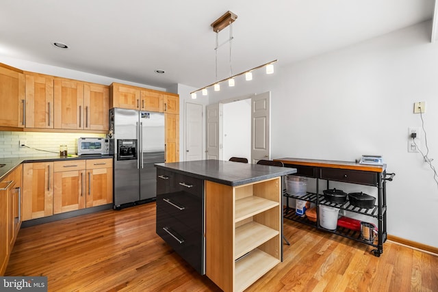kitchen with tasteful backsplash, open shelves, dark countertops, high end fridge, and wood finished floors