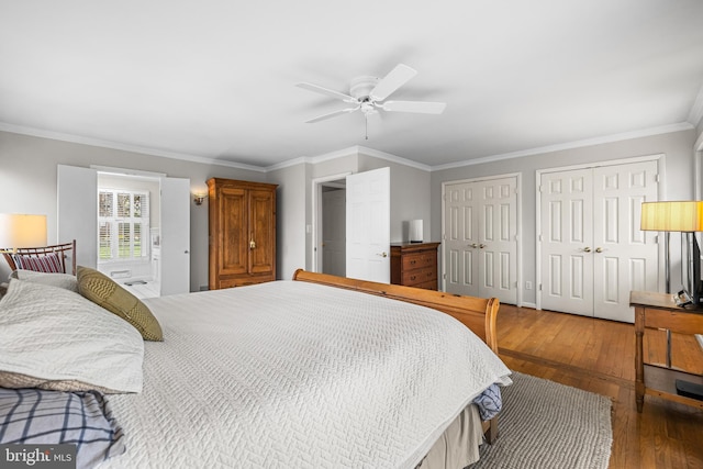 bedroom with crown molding, wood-type flooring, a ceiling fan, and two closets