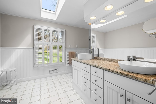 bathroom with tile patterned floors, a sink, and wainscoting