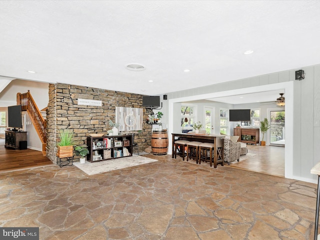 living area featuring a fireplace, stone flooring, recessed lighting, and ceiling fan