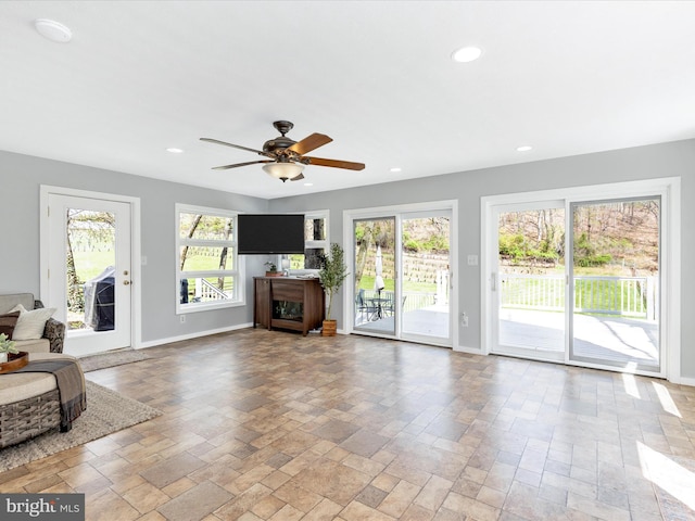 unfurnished living room featuring stone tile floors, plenty of natural light, and baseboards