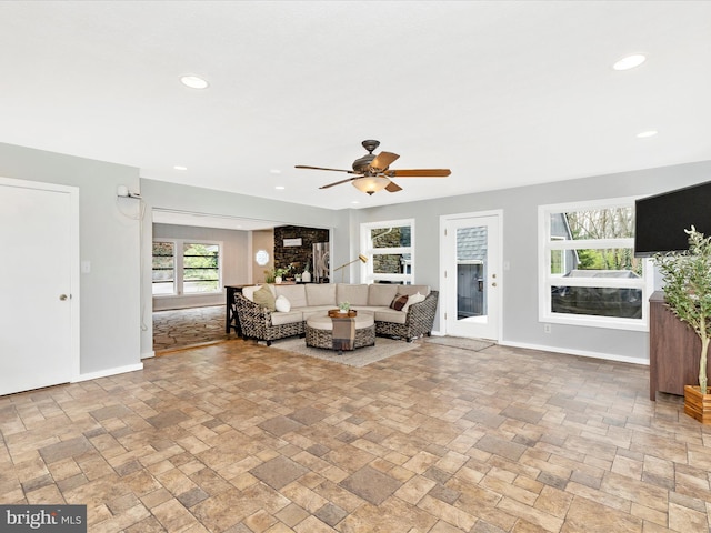 living area featuring recessed lighting, stone tile flooring, a ceiling fan, and baseboards