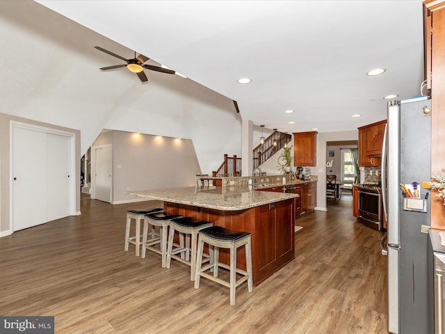 kitchen with stainless steel appliances, recessed lighting, wood finished floors, ceiling fan, and a breakfast bar