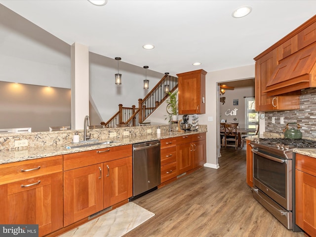 kitchen with light wood-style flooring, a sink, decorative backsplash, light stone countertops, and appliances with stainless steel finishes