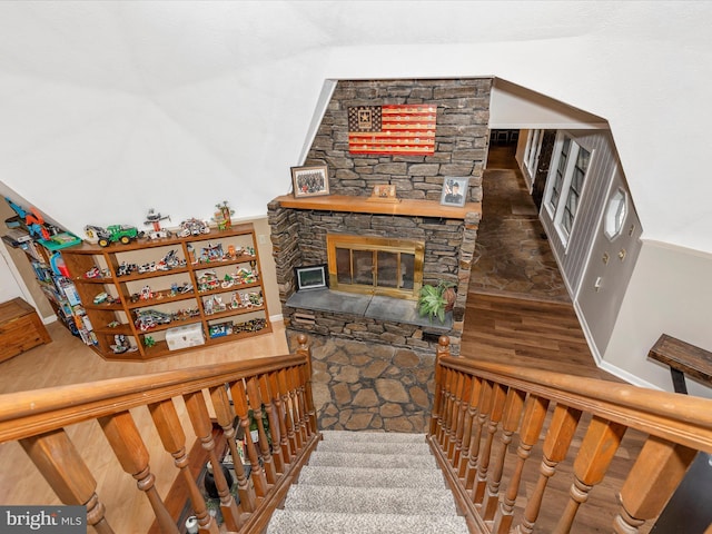 stairs with a stone fireplace, baseboards, and wood finished floors