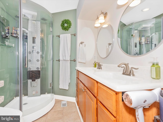 bathroom with tile patterned floors, a stall shower, vanity, baseboards, and visible vents