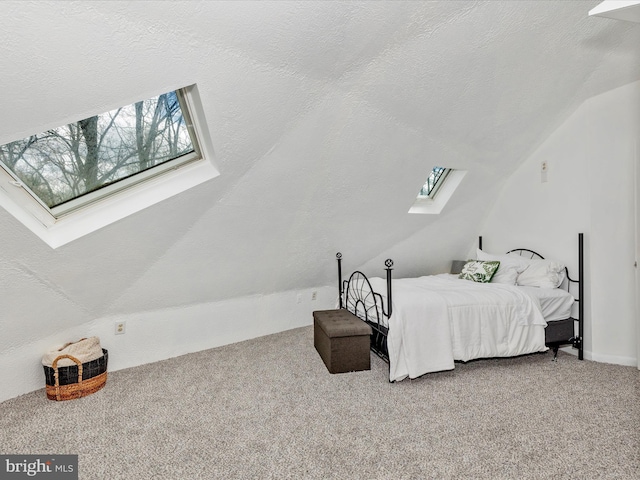 bedroom with vaulted ceiling with skylight, carpet floors, and a textured ceiling