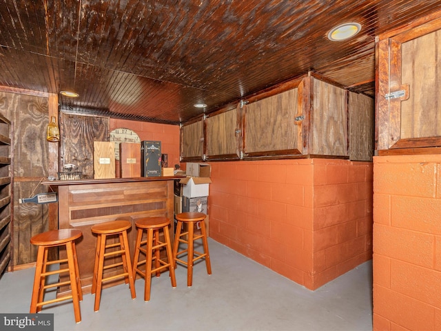 basement with concrete block wall and a bar
