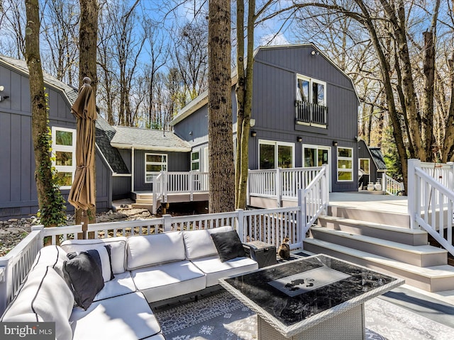 rear view of property featuring a wooden deck, outdoor lounge area, and stairs