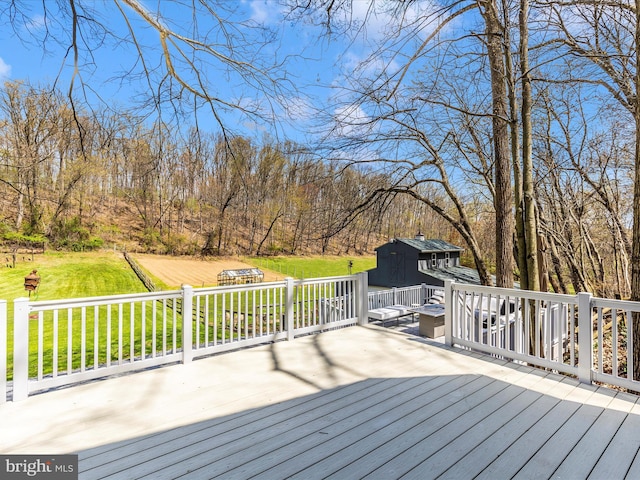 wooden deck with a storage shed, a yard, and an outbuilding