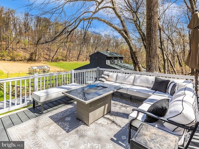 wooden deck featuring an outdoor structure, outdoor lounge area, and a storage shed