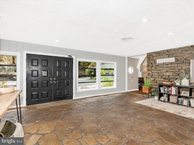 entryway featuring baseboards, a stone fireplace, stone floors, and recessed lighting