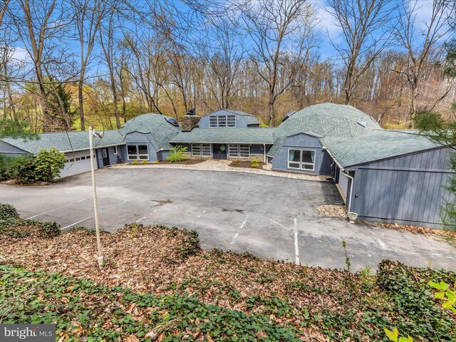 rear view of house featuring a chimney, an attached garage, aphalt driveway, and roof with shingles