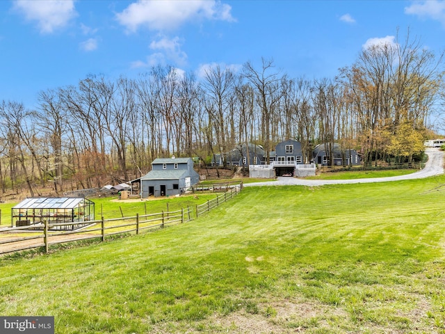view of yard featuring a rural view, an outbuilding, a barn, and fence