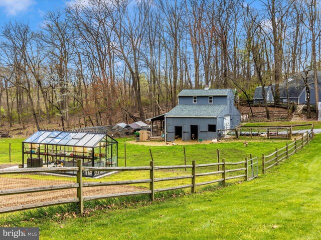 exterior space with an outdoor structure, fence, a yard, and a shingled roof