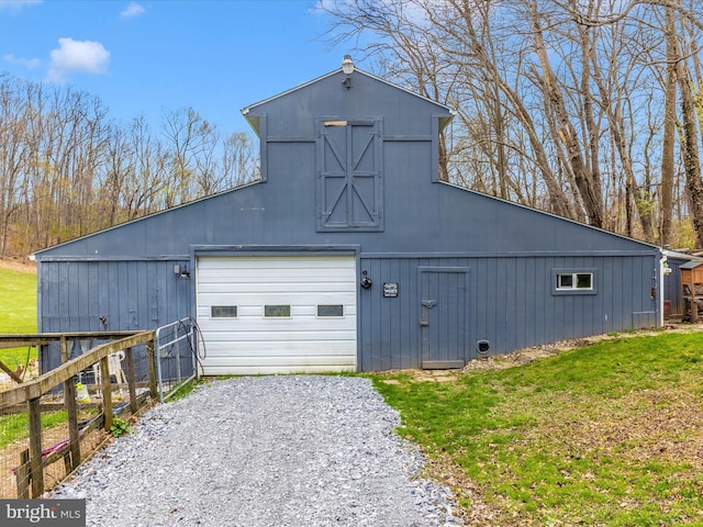 view of barn with a lawn, gravel driveway, and fence