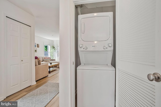 laundry room with stacked washing machine and dryer and wood finished floors