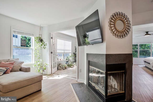 living room featuring a multi sided fireplace, wood finished floors, and ceiling fan