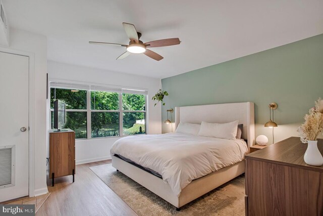 bedroom with light wood finished floors, a ceiling fan, and baseboards