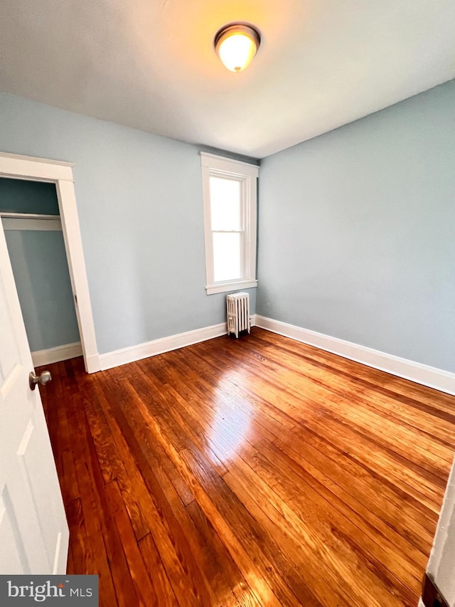 2328 W Lexington St, Baltimore, MD 21223 - unfurnished bedroom with radiator heating unit, hardwood / wood-style floors, and baseboards